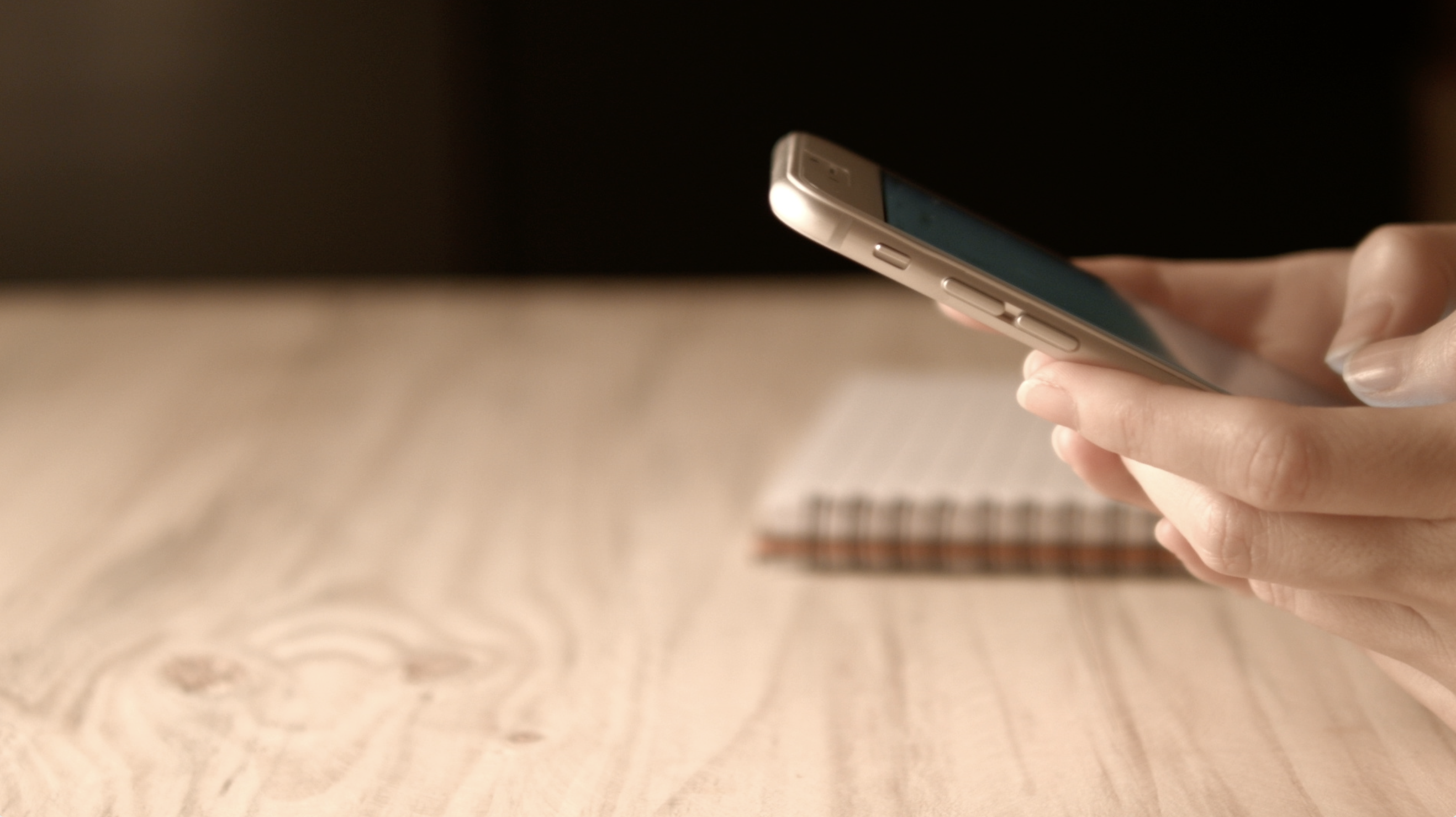 Una persona sostiene su teléfono sobre una mesa de trabajo
